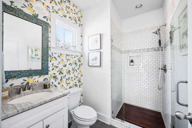 bathroom with toilet, a shower stall, tile patterned flooring, baseboards, and vanity