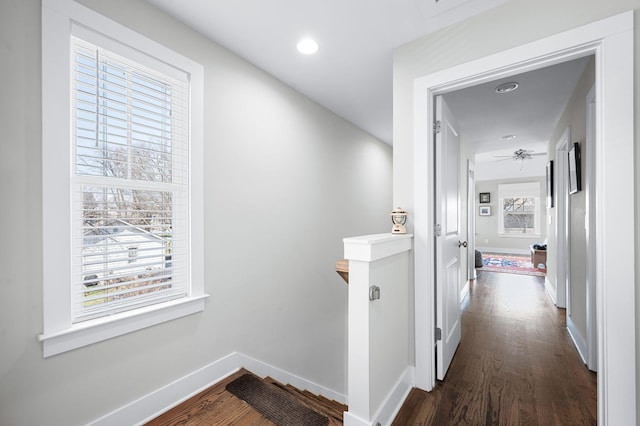 corridor featuring an upstairs landing, recessed lighting, dark wood-type flooring, and baseboards