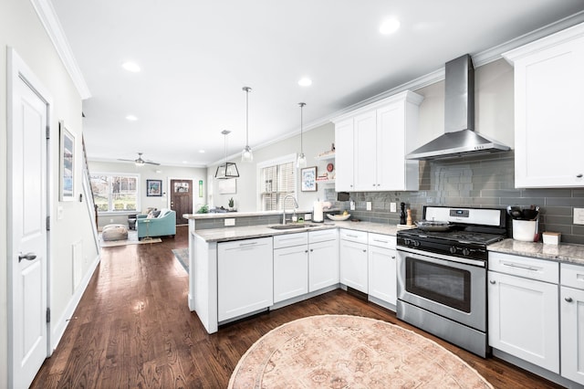 kitchen featuring paneled dishwasher, a sink, gas range, wall chimney range hood, and open floor plan