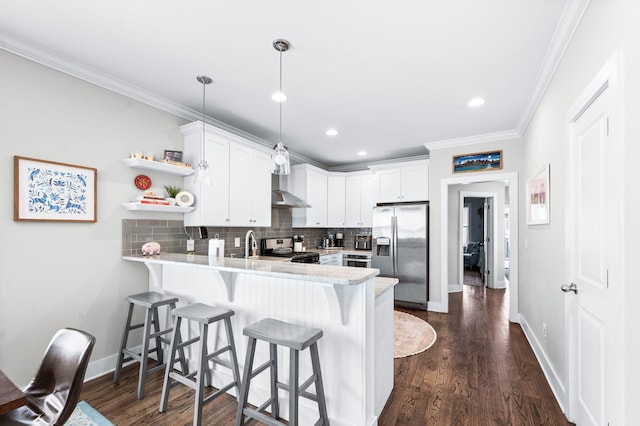 kitchen with wall chimney range hood, ornamental molding, decorative backsplash, a peninsula, and stainless steel appliances