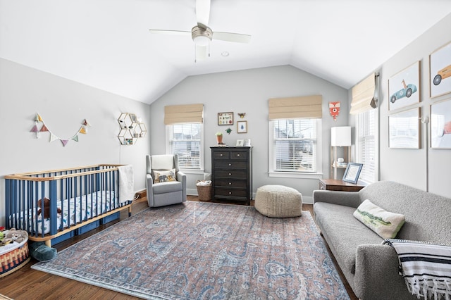 bedroom featuring multiple windows, a crib, lofted ceiling, and wood finished floors