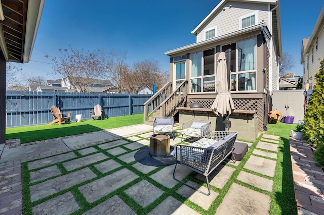 back of property featuring a patio area, a fenced backyard, a sunroom, and a lawn