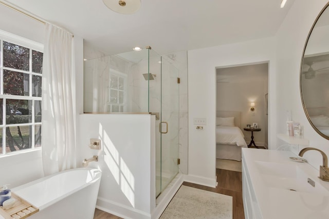 ensuite bathroom with vanity, wood finished floors, a marble finish shower, a freestanding tub, and ensuite bathroom