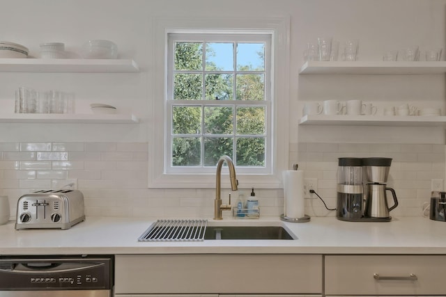 kitchen featuring a sink, dishwashing machine, light countertops, and open shelves