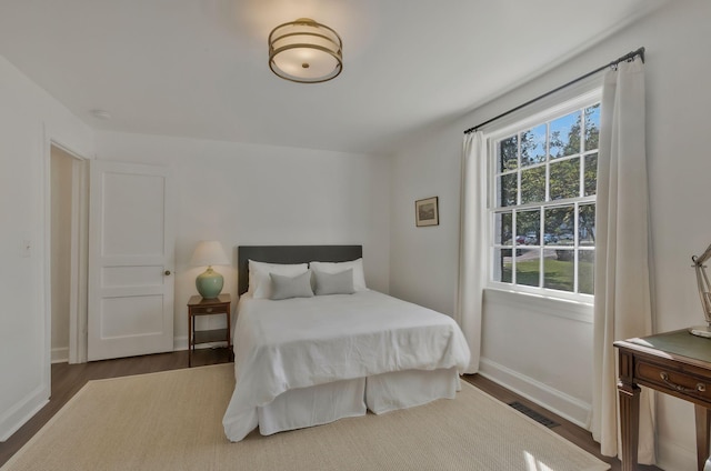 bedroom featuring visible vents, baseboards, and wood finished floors