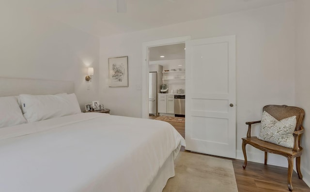 bedroom featuring stainless steel fridge, ensuite bath, and light wood-style floors