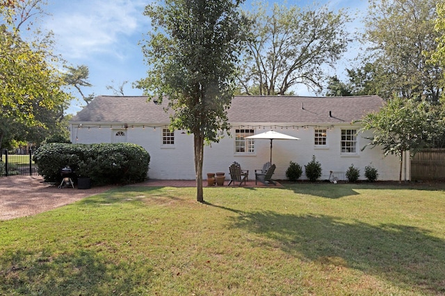 back of house with brick siding, a patio, fence, and a lawn