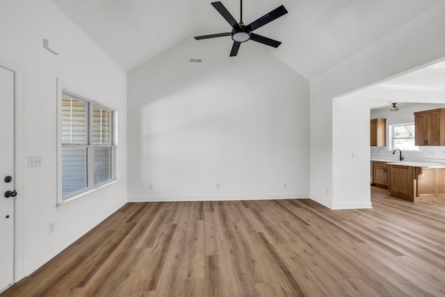 unfurnished living room with light wood finished floors, visible vents, baseboards, ceiling fan, and a sink