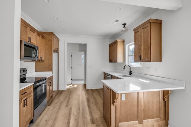 kitchen featuring a sink, appliances with stainless steel finishes, a peninsula, and brown cabinetry