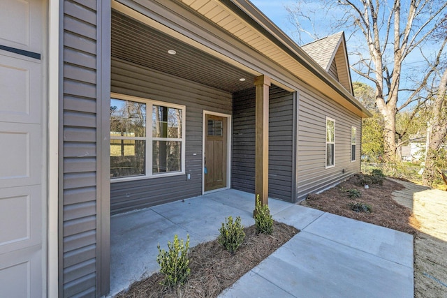 view of exterior entry featuring a shingled roof