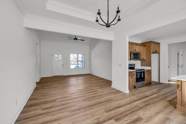 kitchen with brown cabinetry, a tray ceiling, light countertops, light wood-style floors, and appliances with stainless steel finishes