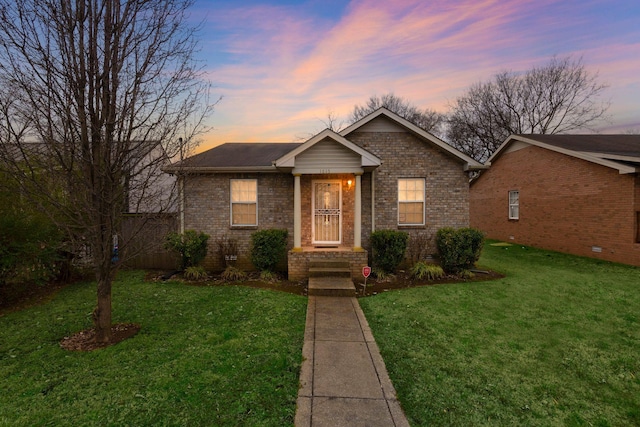 view of front of house featuring a yard and brick siding