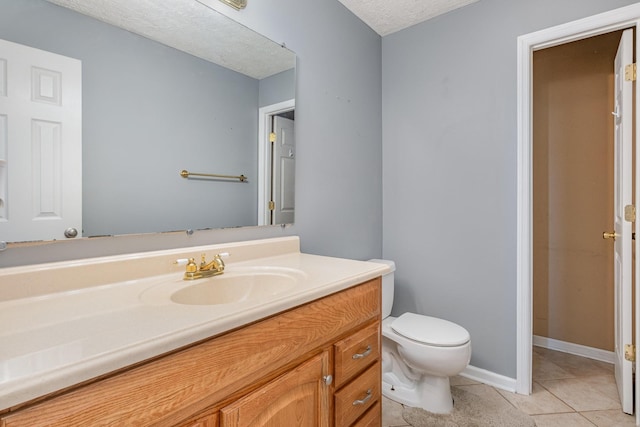 bathroom featuring toilet, a textured ceiling, tile patterned flooring, baseboards, and vanity