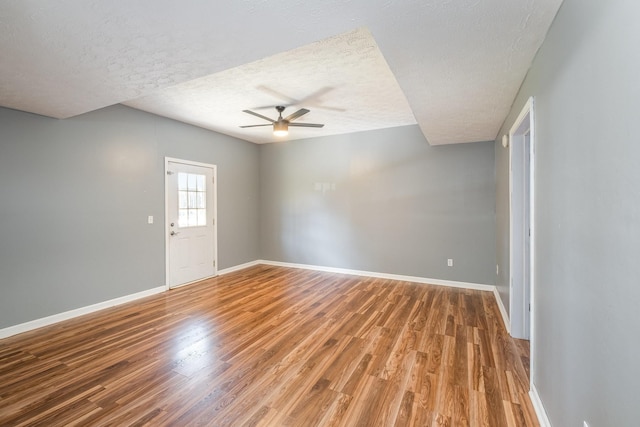 spare room with a textured ceiling, baseboards, and wood finished floors