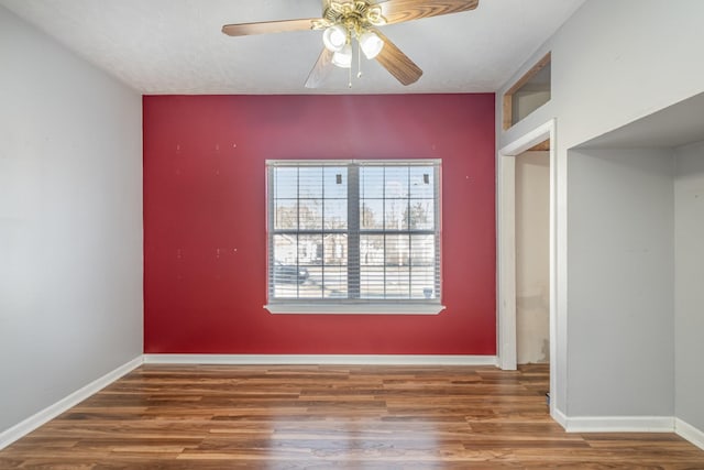 empty room featuring a ceiling fan, baseboards, and wood finished floors