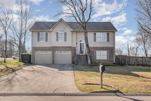 bi-level home with a front yard, fence, driveway, an attached garage, and brick siding