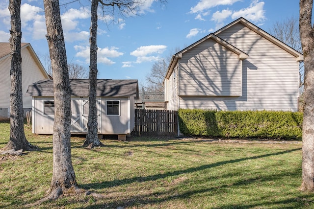 view of home's exterior with a yard, an outbuilding, and fence