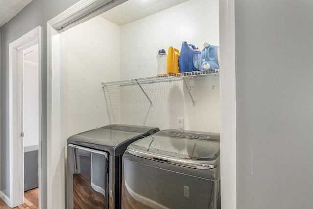 clothes washing area with laundry area, wood finished floors, and separate washer and dryer