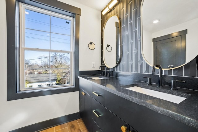 bathroom with double vanity, wood finished floors, baseboards, and a sink