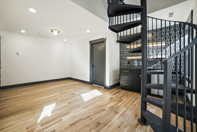 interior space featuring recessed lighting, baseboards, light wood-style floors, and stairs