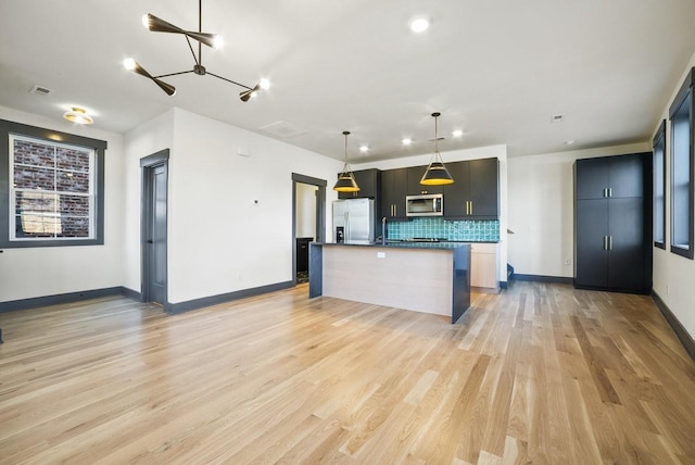 kitchen with visible vents, decorative light fixtures, tasteful backsplash, stainless steel appliances, and light wood finished floors