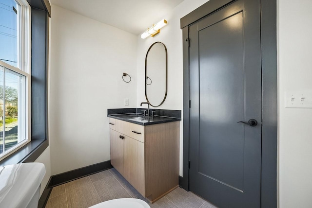 bathroom with baseboards, toilet, and vanity