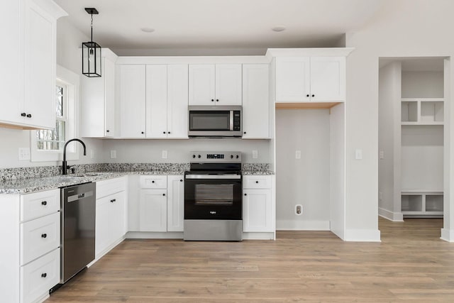 kitchen with white cabinets, light stone countertops, appliances with stainless steel finishes, and a sink