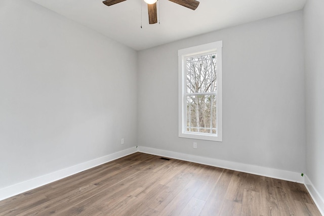 spare room featuring visible vents, baseboards, wood finished floors, and a ceiling fan