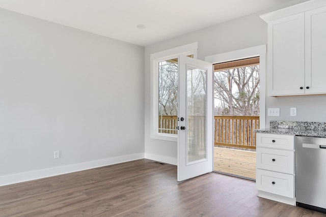 interior space featuring stainless steel dishwasher, dark wood-type flooring, baseboards, and white cabinetry