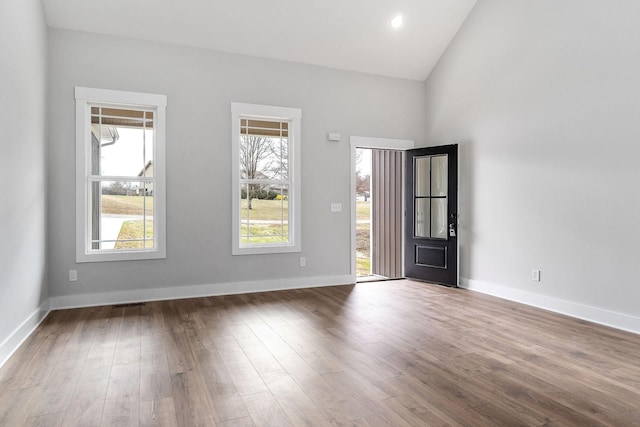 spare room featuring recessed lighting, baseboards, wood finished floors, and vaulted ceiling