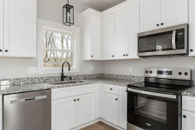 kitchen featuring white cabinets, light stone counters, appliances with stainless steel finishes, and a sink