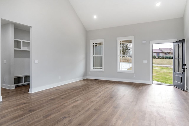 unfurnished living room featuring recessed lighting, high vaulted ceiling, baseboards, and wood finished floors