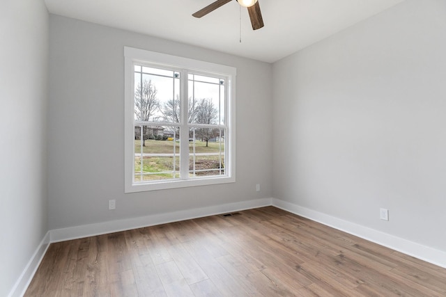 spare room featuring visible vents, wood finished floors, baseboards, and ceiling fan