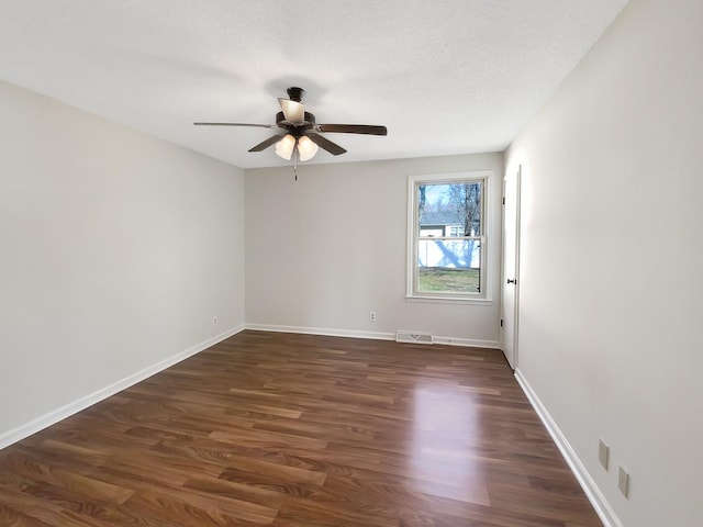 empty room featuring visible vents, baseboards, dark wood finished floors, a textured ceiling, and a ceiling fan