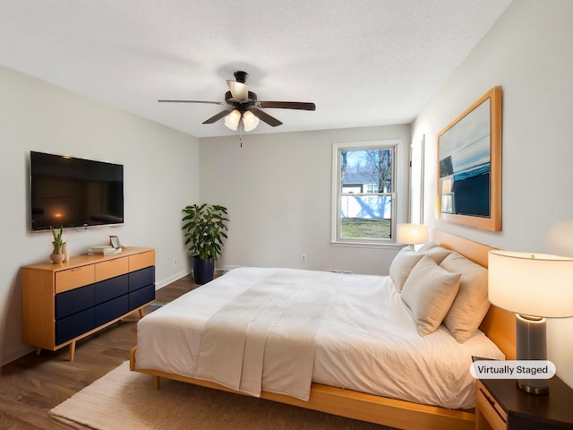 bedroom with a ceiling fan, wood finished floors, baseboards, and a textured ceiling