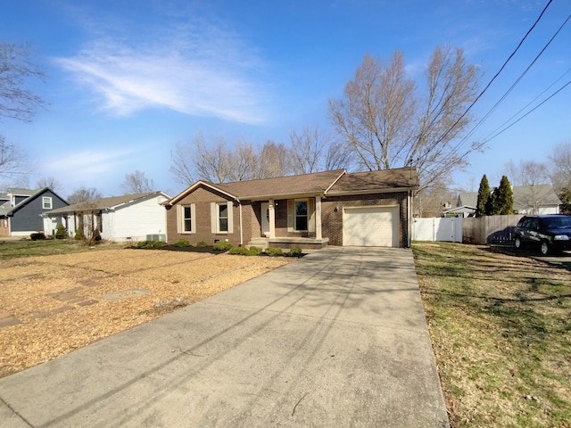 ranch-style home with a garage, brick siding, driveway, and fence