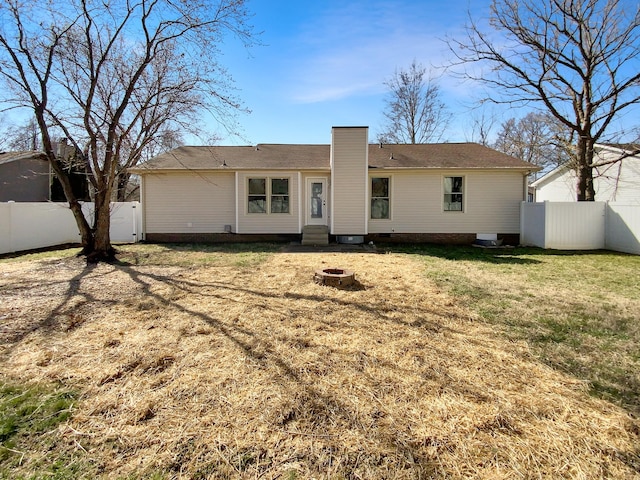 back of house with a lawn, a fenced backyard, entry steps, and an outdoor fire pit