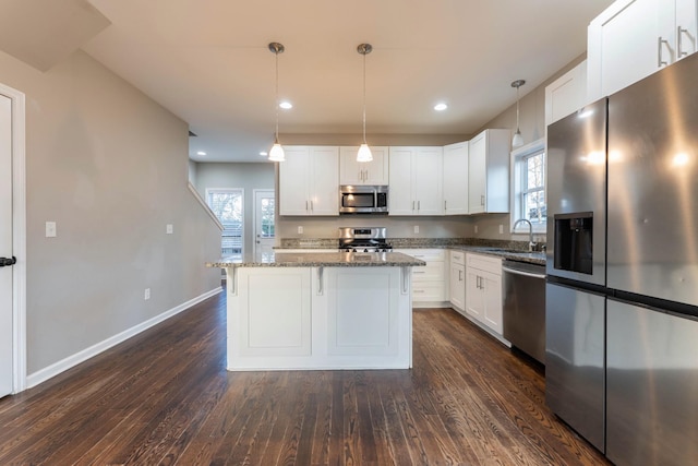 kitchen with dark stone counters, appliances with stainless steel finishes, dark wood finished floors, and a center island