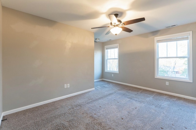 unfurnished room featuring carpet flooring, baseboards, visible vents, and ceiling fan