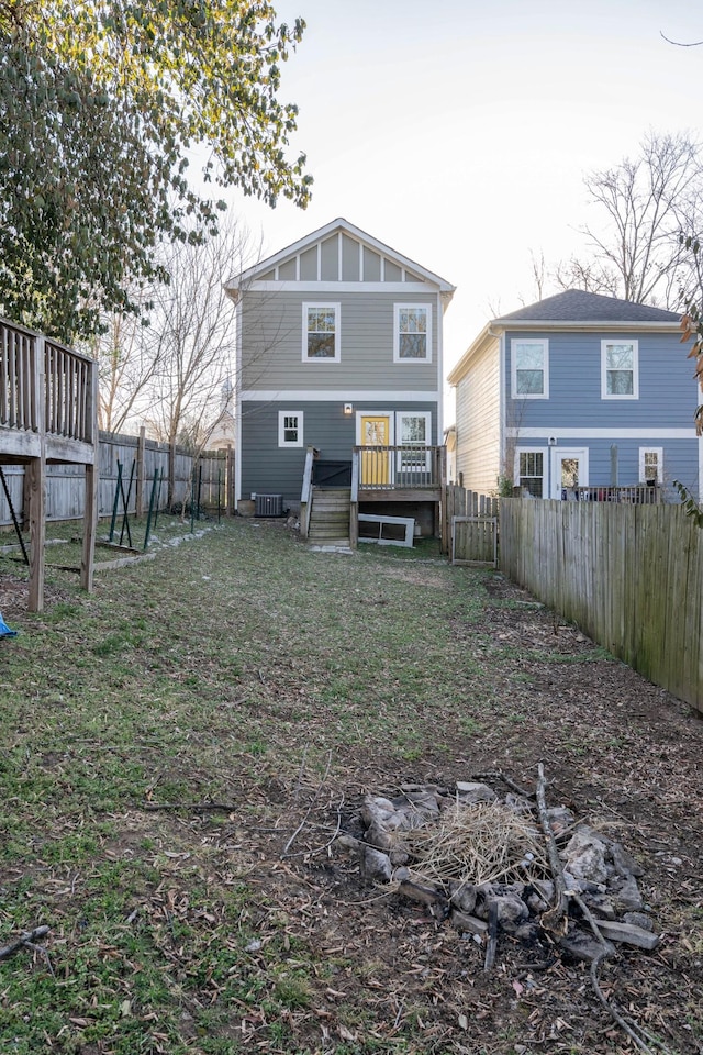 rear view of house with a lawn, board and batten siding, a wooden deck, and a fenced backyard