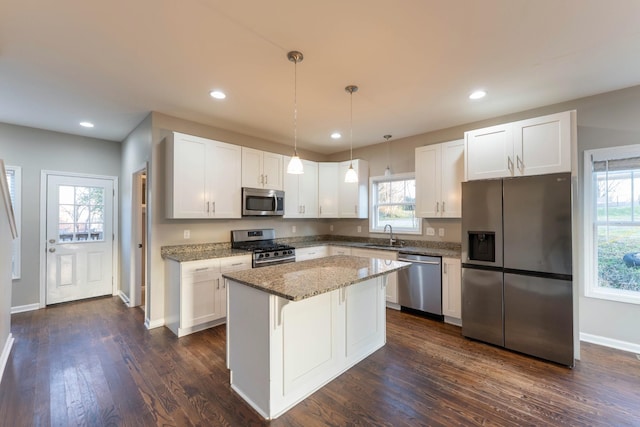 kitchen with dark wood-style floors, a kitchen island, plenty of natural light, stainless steel appliances, and white cabinetry