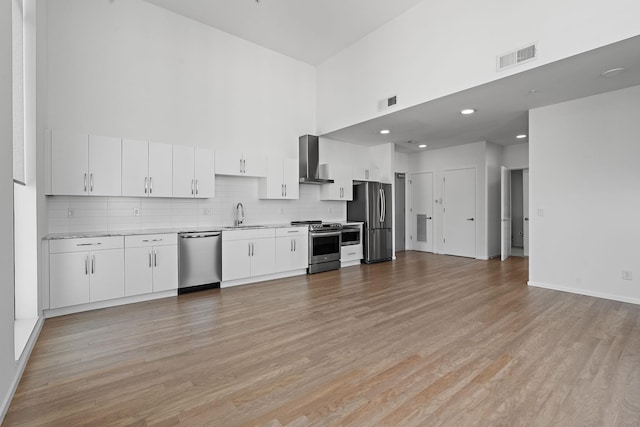 kitchen with a sink, light countertops, wall chimney exhaust hood, and stainless steel appliances