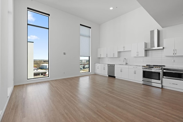 kitchen with decorative backsplash, light countertops, wall chimney exhaust hood, and stainless steel appliances