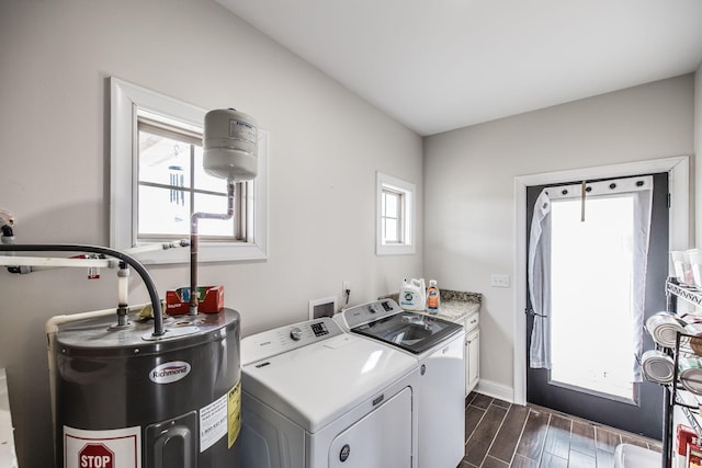 laundry area with baseboards, wood tiled floor, separate washer and dryer, cabinet space, and water heater