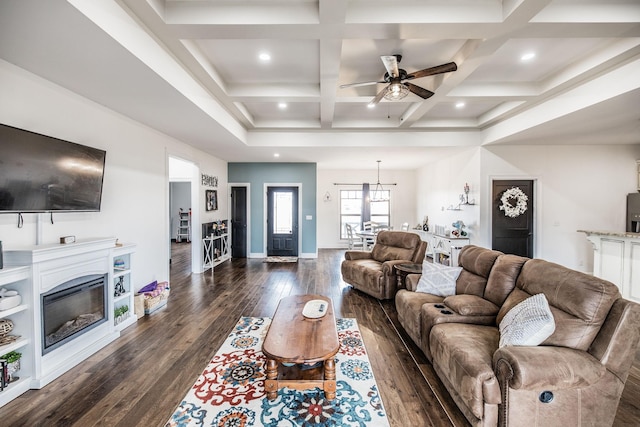 living area featuring dark wood-type flooring, baseboards, beamed ceiling, a glass covered fireplace, and coffered ceiling