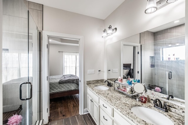 ensuite bathroom featuring a sink, wood finished floors, a stall shower, and ensuite bath