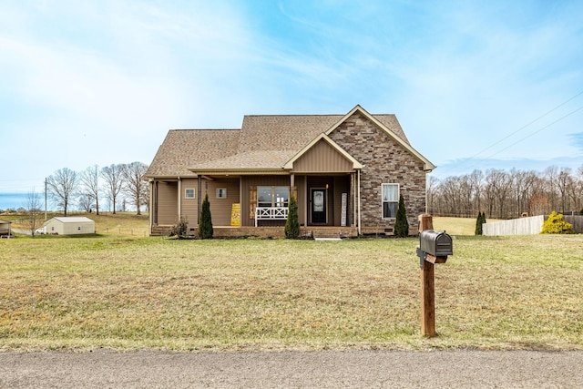 view of front of house featuring a front lawn, fence, a porch, roof with shingles, and stone siding