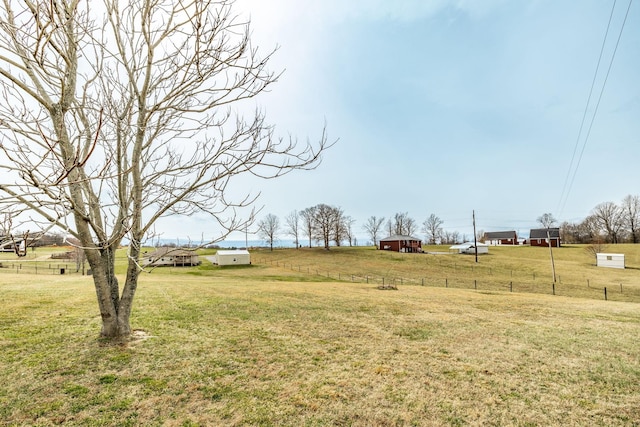 view of yard with a rural view, an outdoor structure, and fence