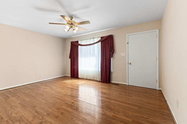 unfurnished room with visible vents, baseboards, ceiling fan, and wood finished floors
