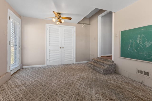 carpeted spare room with visible vents, baseboards, and a ceiling fan